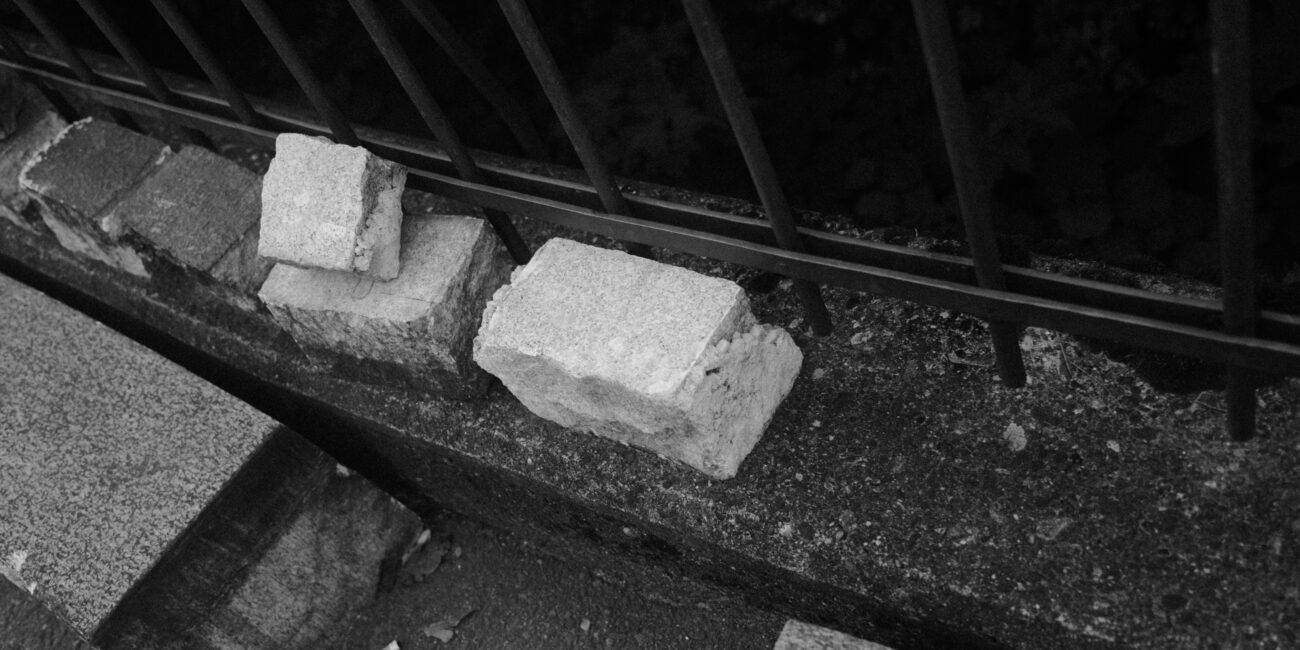 Steine liegen auf einer Mauer vor einem Metallzaun