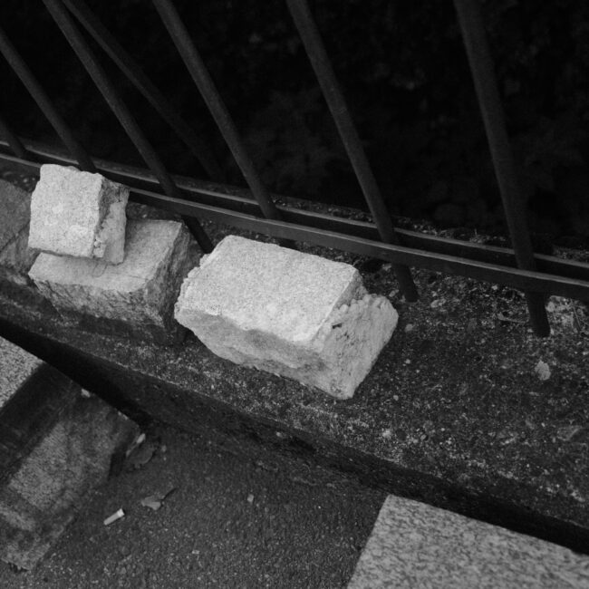 Steine liegen auf einer Mauer vor einem Metallzaun
