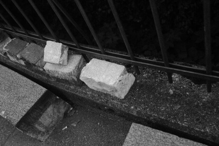 Steine liegen auf einer Mauer vor einem Metallzaun